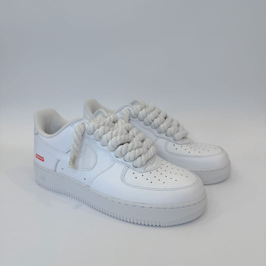 Pár custom Nike Air Force 1 Low Supreme White – minimalistické biele tenisky s prémiovými bielymi rope šnúrkami.